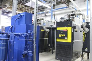A compressed air system with Zeks and Quincy parts are assorted in a room.
