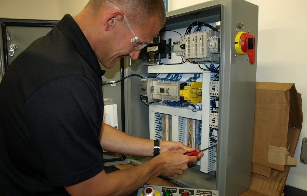 A JHFoster employee works on an electrical panel.