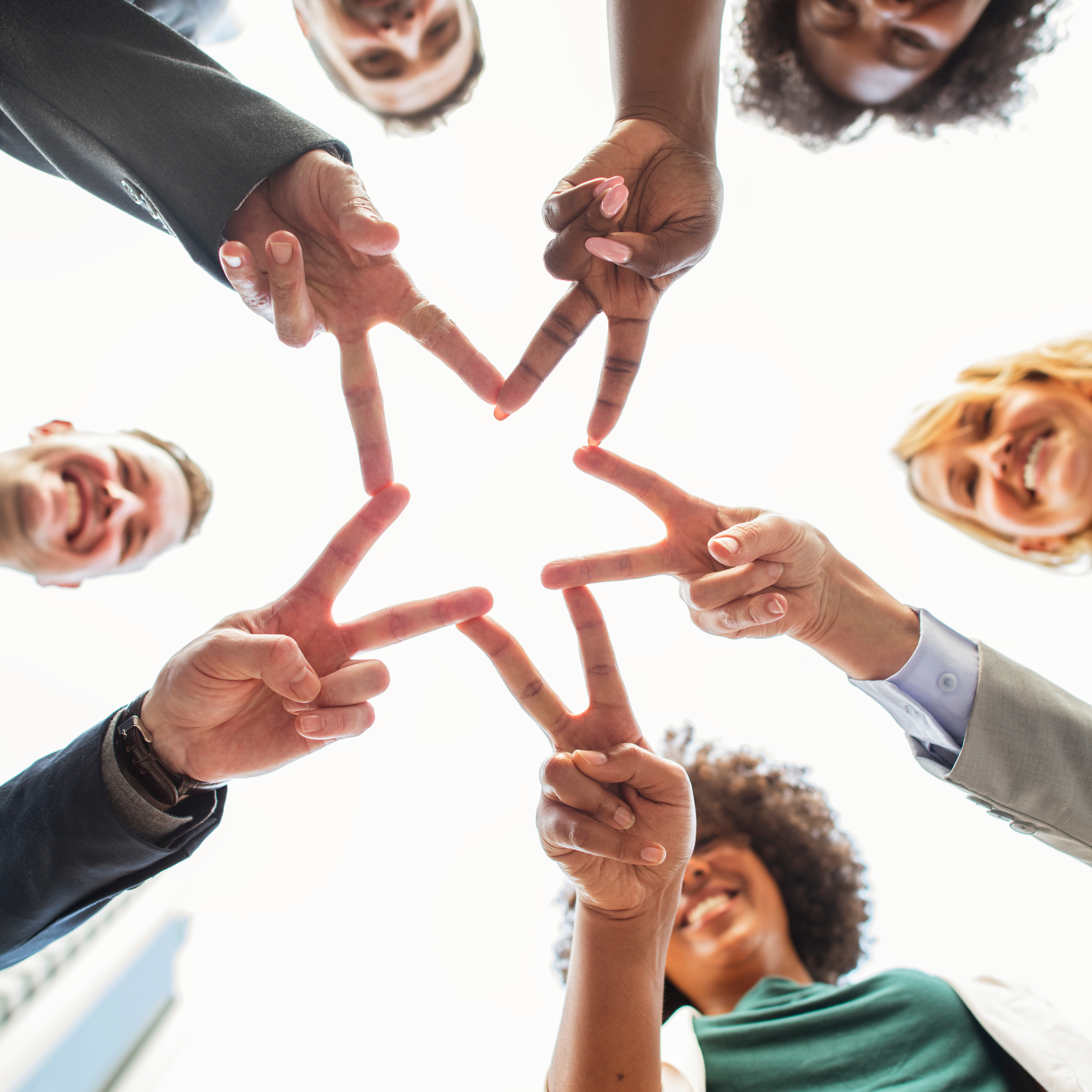 Business people create a star with joined hands showing the connection of departments and work.