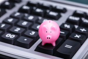 Close-up Of Small Pink Piggy Bank On Calculator